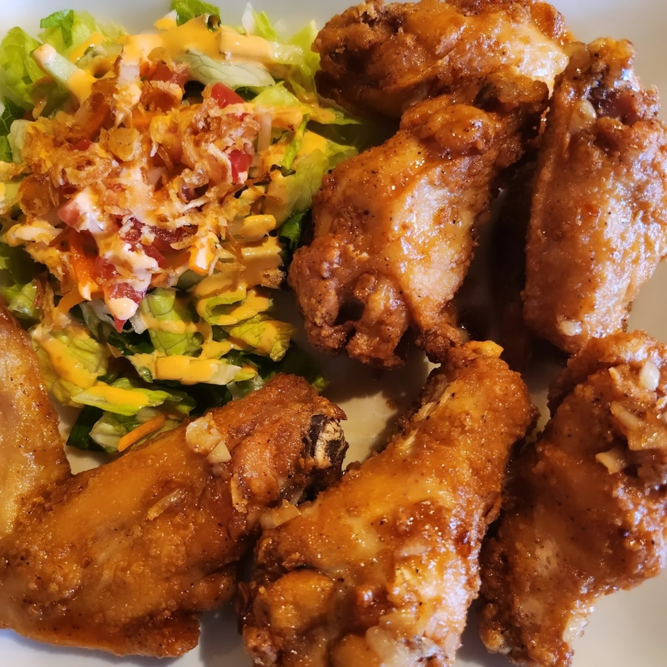 Crispy Vietnamese chicken wings with a side salad topped with dressing and fried onions.